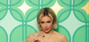 Kat Ryder porn model in pink, with her hands on her boobs
